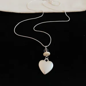 Macro view showing close-up detail of silver heart pendant necklace with cream bead accents