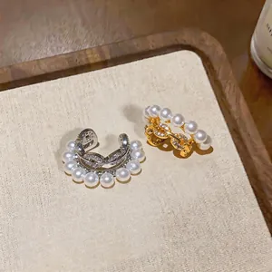 Macro view of luxury pearl ear cuffs with pavé zirconia stones in gold and silver.