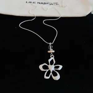 Detailed view of silver flower pendant necklace with heart center on black velvet
