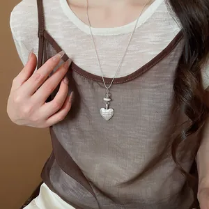 Detailed close-up view of a silver heart pendant necklace with 'Eternal my love' engraving.