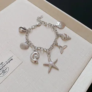 Nahaufnahme eines silbernen Armbands mit Meeresmotiven, Seesternen und kleinen Muscheln