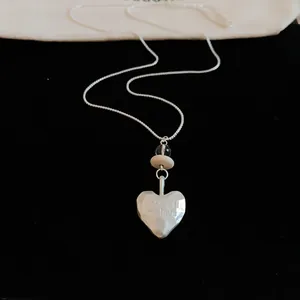 Close-up of silver heart pendant with Eternal my love engraving on black velvet