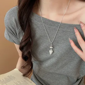 Elegant silver chain necklace with a unique textured pinecone pendant worn by a model