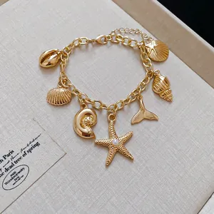 Nahaufnahme goldener Anhänger wie Muscheln und Seesterne an einem verstellbaren Armband
