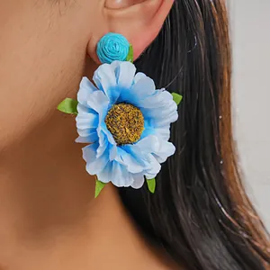 Detailansicht eines eleganten blauen Raffia-Stoffblumen-Ohrrings an einem Modell im Fokus