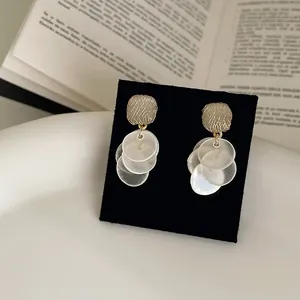 Detailed macro view of elegant cat's eye stone earrings with white translucent disc tassels