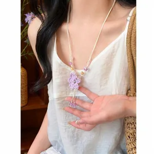 Handmade woven purple flower pendant necklace with beads on a model in sunlight