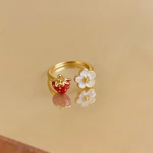 Exquisite close-up view of golden open ring featuring red strawberry and white flower charms