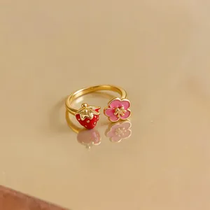 Detailed view of adjustable gold-plated ring with red strawberry and pink flower motifs