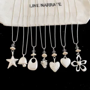Close-up detail of silver geometric necklaces with star, heart and flower pendants