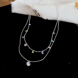 Détail du collier double rang avec pierres colorées et pendentif en cristal clair