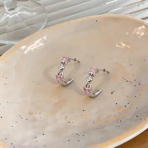 Detailed macro shot of elegant C-shaped earrings featuring pink heart-shaped zircons