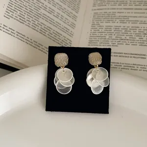 Detail view of round tassel stud earrings with cat's eye stone and grid metal