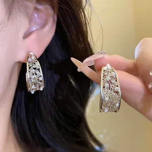 Dettaglio di eleganti orecchini a forma di C traforati con intarsi di perle in argento