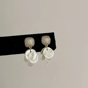 Detailed close-up of cat's eye stone earrings featuring shimmering white round shell tassels