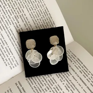 Detailed macro view of cat's eye stone earrings with white round tassel on black card