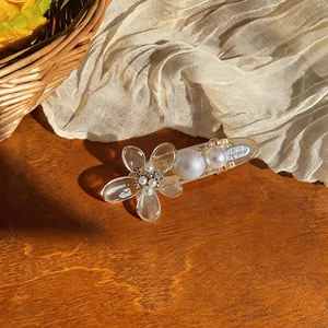 Close-up detail of the elegant acrylic flower hair clip with pearls and sparkling rhinestones