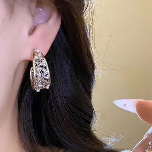 Primo piano dei dettagli degli orecchini a C traforati con perle decorative raffinate