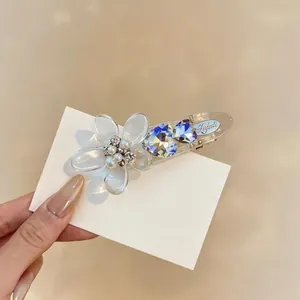Close-up of an elegant acrylic flower hair clip with pearls and blue heart crystals.