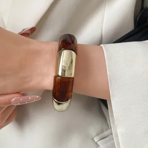Close-up of a Maillard-style acrylic and gold spliced bangle on a woman's wrist.