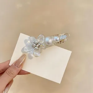 Close-up of elegant acrylic flower hair clip with pearls on a white display card