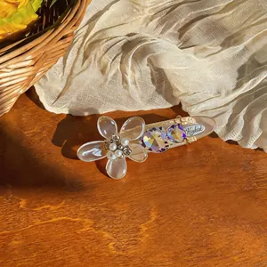 Macro view of an elegant acrylic flower hair clip featuring pearls and purple crystals