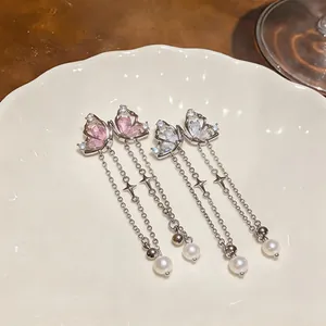 Elegant zircon butterfly tassel earrings with pearls and star details on a white plate.