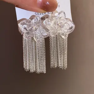 Dettaglio di orecchini a fiore in resina trasparente con lunghe nappe a catena argentata