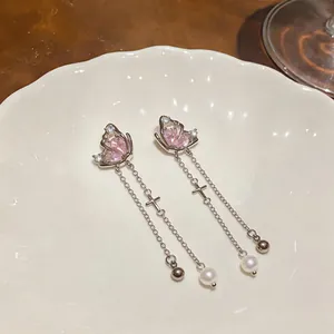 Close-up detail of silver butterfly tassel earrings with pink zircon stones and pearls