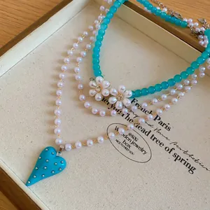 Detail of multi-layer pearl necklace with turquoise heart pendant and flower beads