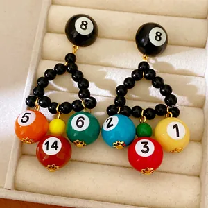 Gros plan de boucles d'oreilles boule de billard 8 avec charms multicolores