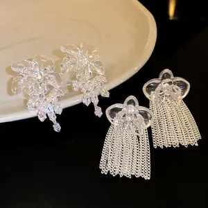 Dettaglio di orecchini a fiore in resina con zircone e nappe a catena lunga