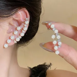 Close-up of French vintage pearl and crystal asymmetric earrings on ear and hand
