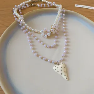 Detailed macro shot of a three-layered pearl necklace with heart and flower pendants