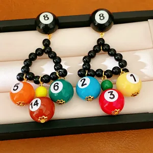 Détail de boucles d'oreilles boules de billard avec breloques numérotées colorées