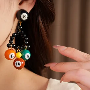 Détail des boucles d'oreilles boules de billard uniques en résine avec numéros.