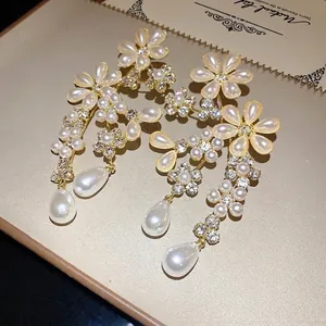 Elegant vintage floral earrings with pearls and rhinestones on a textured background.
