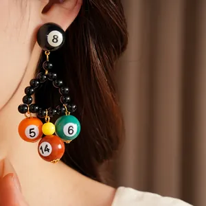 Gros plan de boucles d'oreilles boules de billard avec perles noires et sphères en résine.