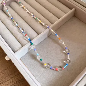 Detail of colorful rainbow beads interspersed with clear crystal beads in a grey velvet tray
