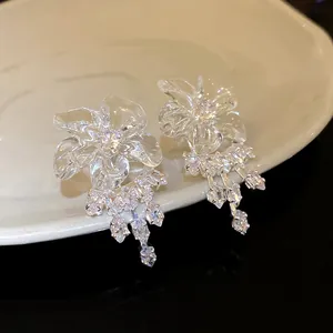 Vista ravvicinata di orecchini a fiore in resina con nappe di zirconi su un piatto di ceramica