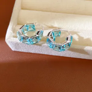 Primo piano di eleganti orecchini a cerchio color argento con zirconi quadrati azzurri