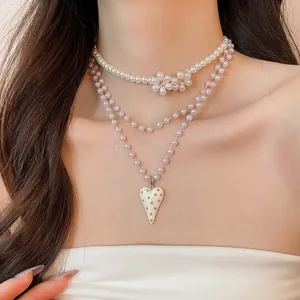 Detailed view of elegant multi-layered pearl necklace with heart pendant and flower accents