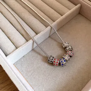 Close-up of bohemian snake chain necklace with colorful crystal encrusted charms in a box