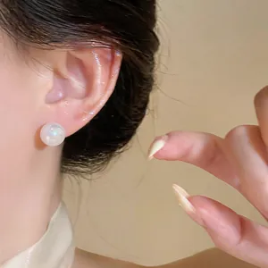 Close-up of an elegant French vintage white pearl stud earring worn on a model's ear