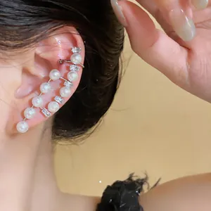 Close-up view of an elegant asymmetric pearl and zircon ear cuff earring worn on ear