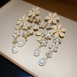Close-up of elegant floral earrings with pearls and crystals on a creamy luxury background