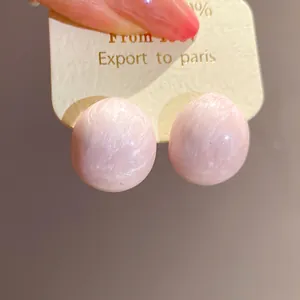 Detailed view of minimalist pink marbled oval stud earrings on a white display card