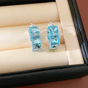 Primo piano dettagliato di eleganti orecchini a cerchio in argento con zirconi blu quadrati