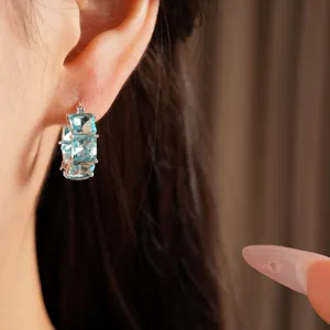 Primo piano di orecchini a cerchio argento con pietre di zircone blu chiaro quadrate