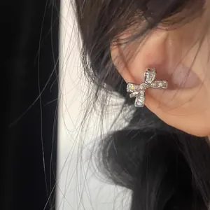 Detailed view of a silver bow ear cuff adorned with sparkling cubic zirconia on an ear